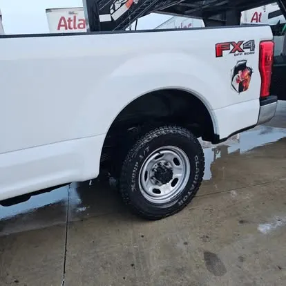 White work pickup truck just washed, wet pavement around it