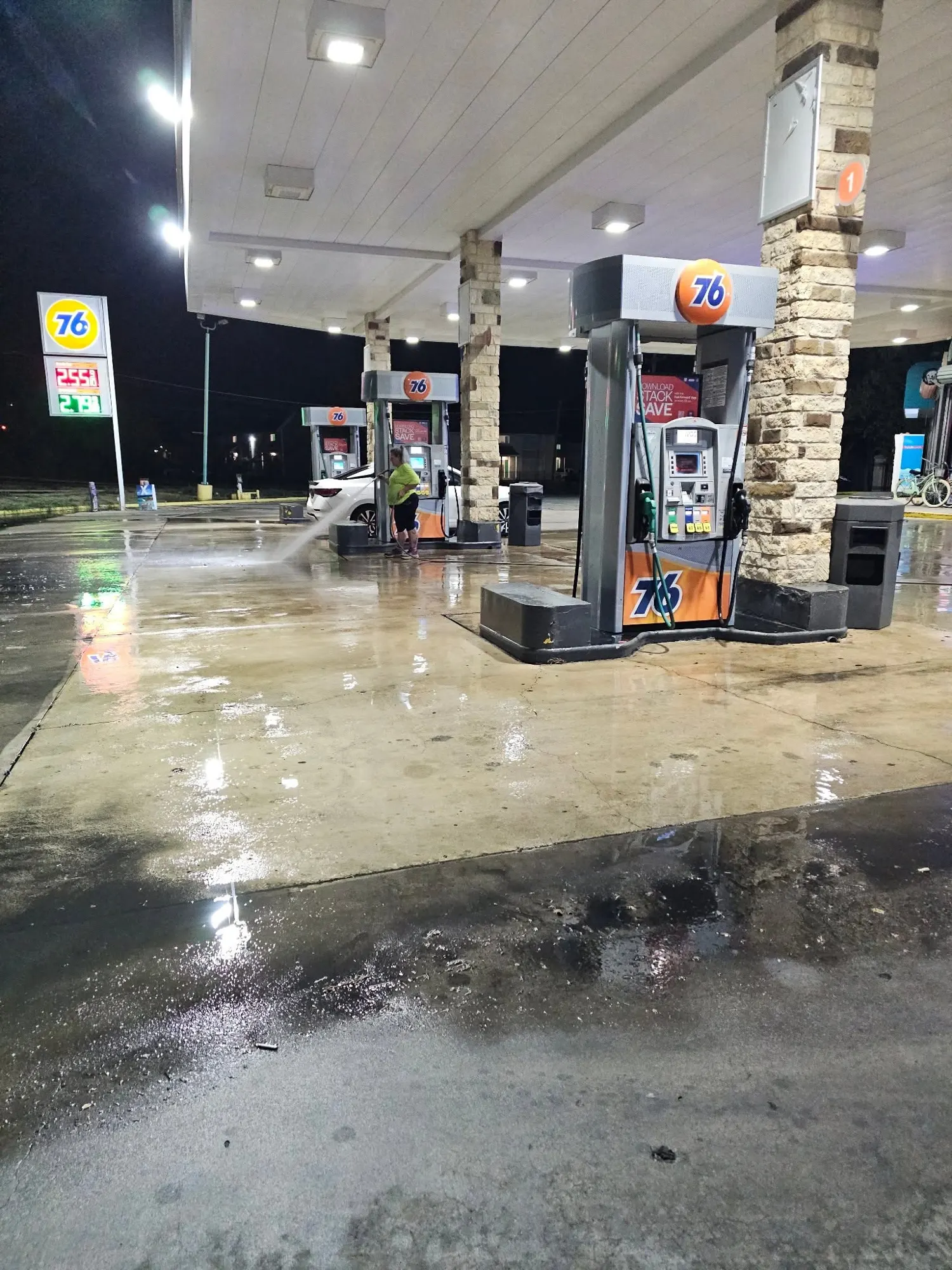 Premier Pro crew power washing a gas station forecourt at night under the canopy lights