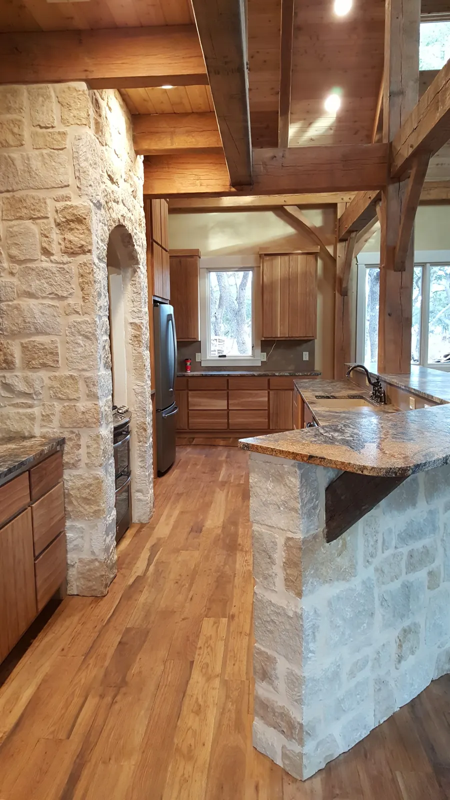 Clean kitchen with stone walls, wood floors and timber beams